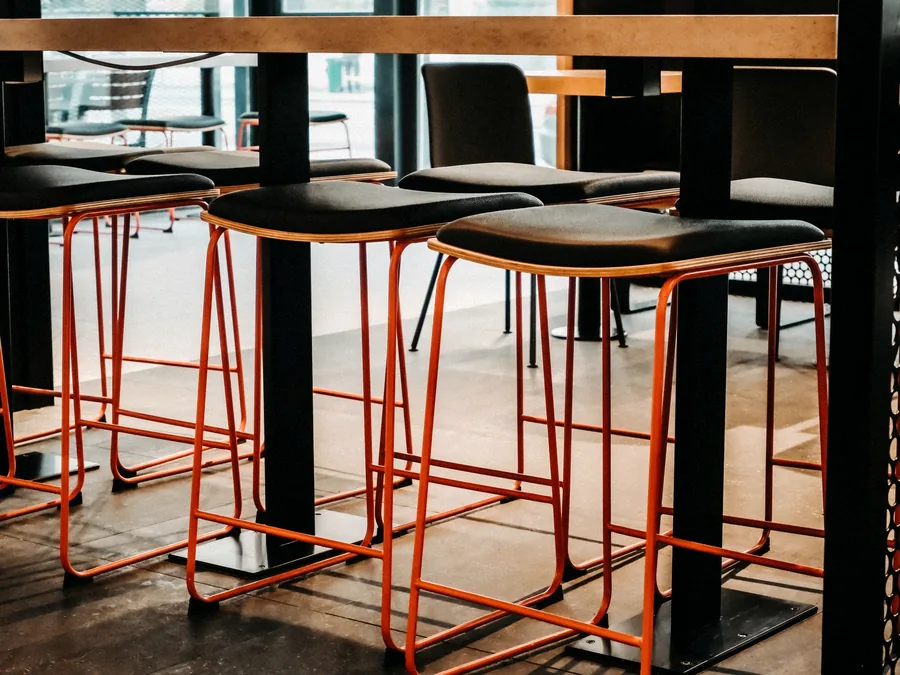 Kursi barstool tinggi mengelilingi meja bar kayu